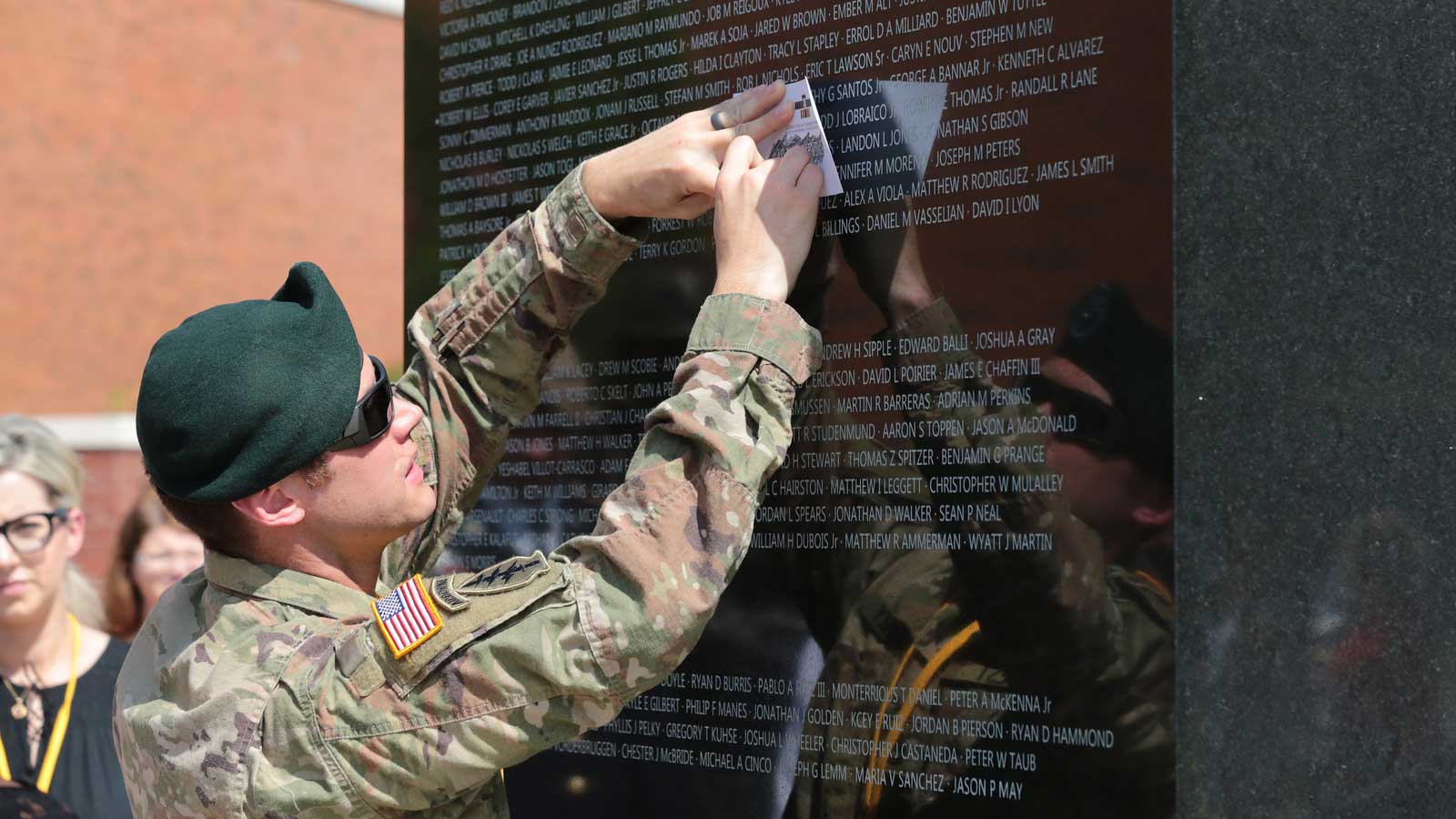 Attendees of the Global War on Terrorism Memorial rededication ceremony take rubbings of the new names etched into the granite panels.